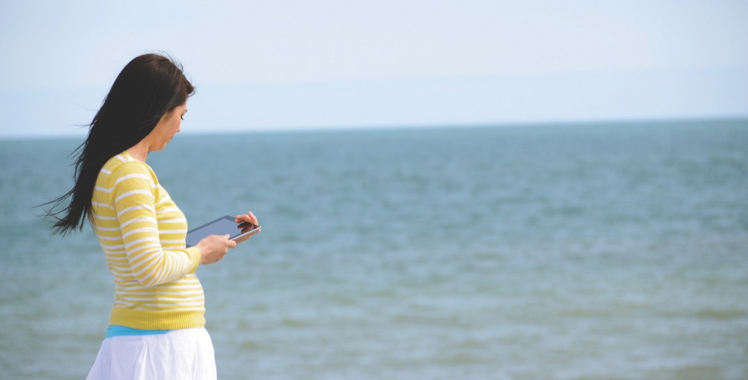 Woman reading on tablet at beach