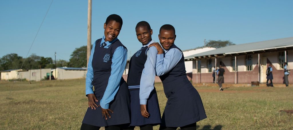 Three girls smiling outside school